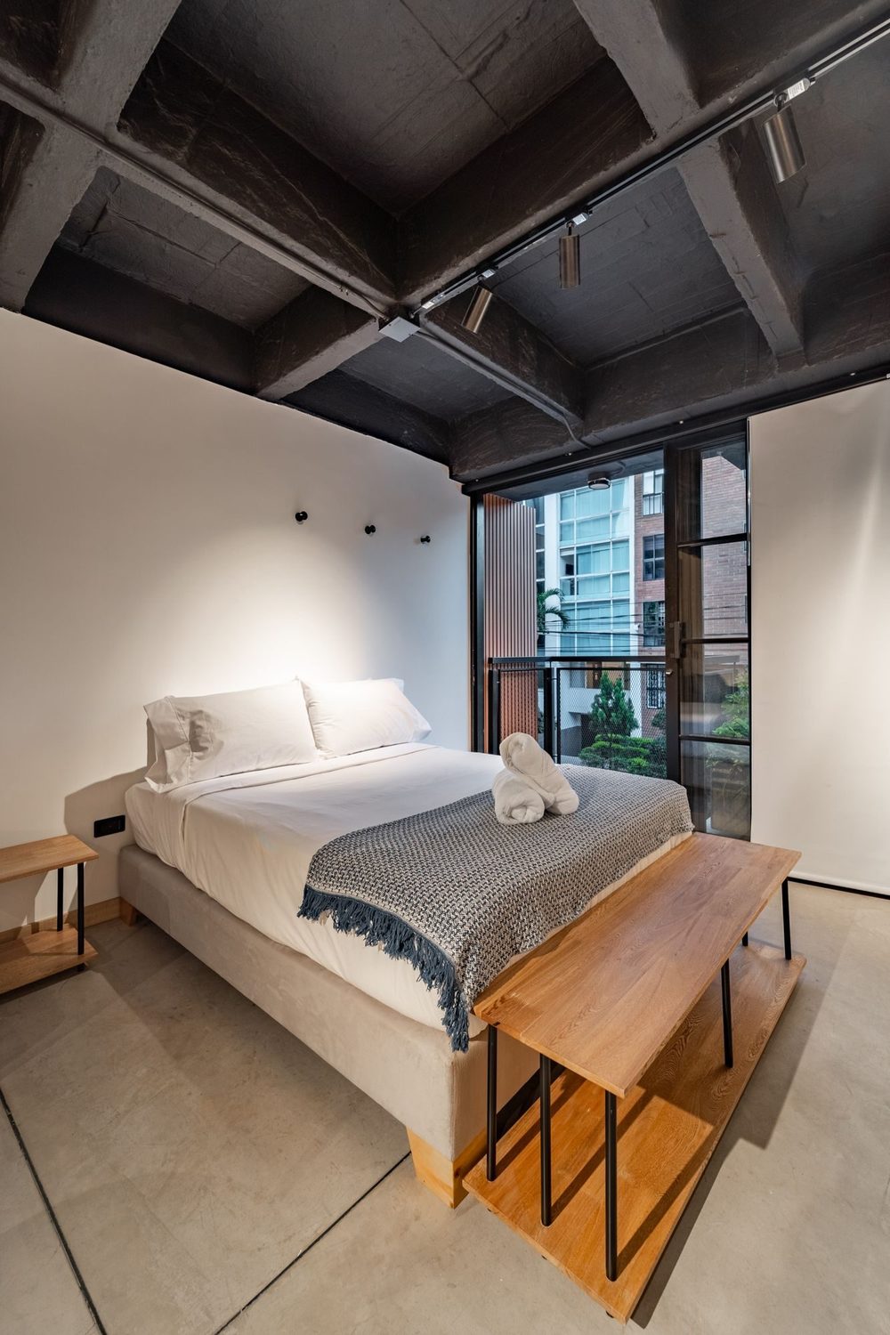 Habitación con cama doble y salida a un balcón con vista al barrio